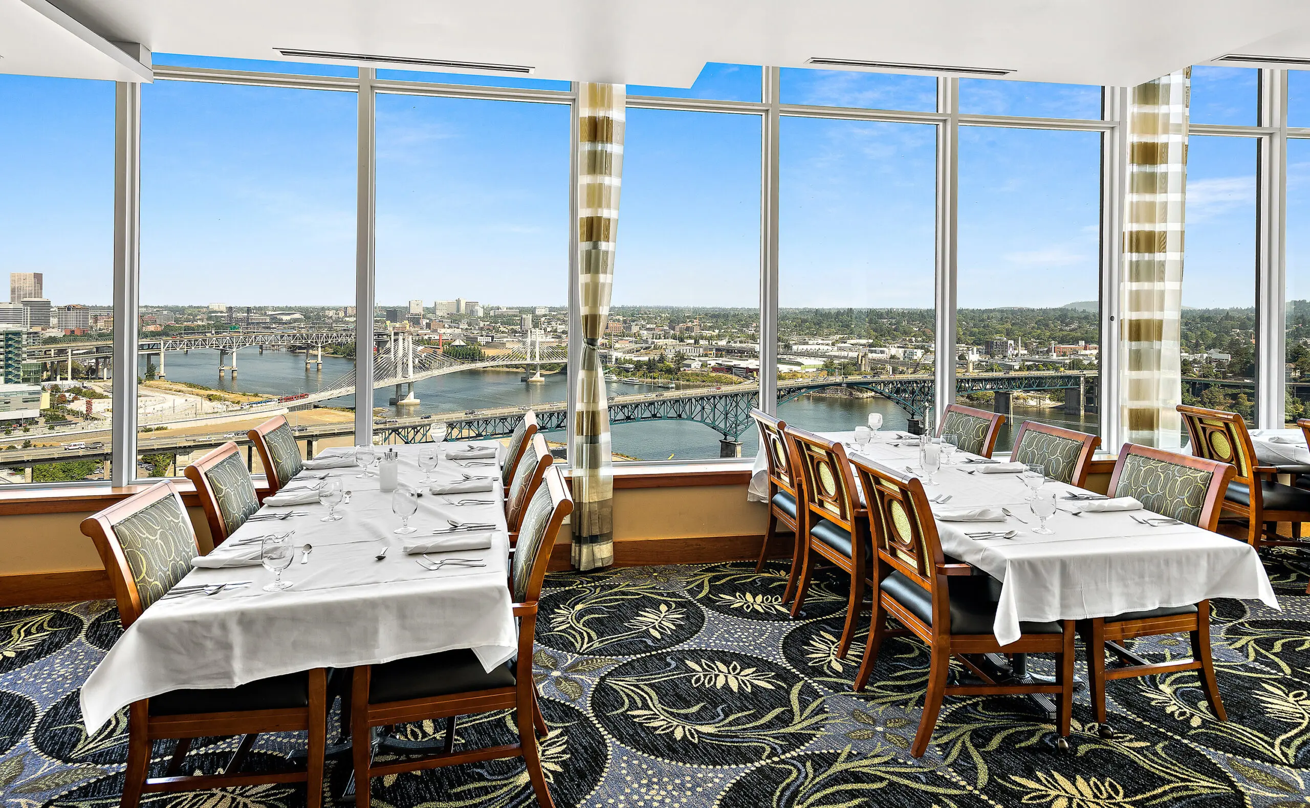 Photo of a fine dining room at Mirabella Portland. The room is surrounded by large windows.